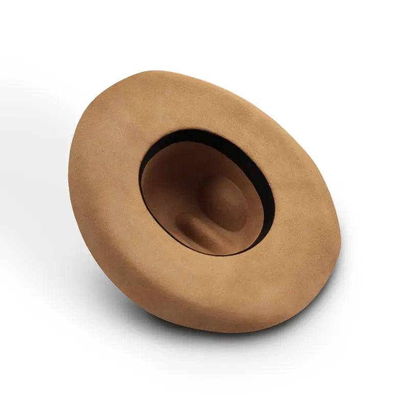 On a city street, a woman wearing a camel coat and a beige felt wide-brimmed cowboy hat.