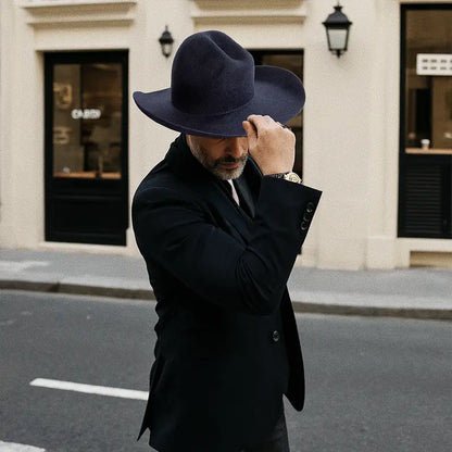 Outside a building with a black awning, a formally dressed man wore a navy blue, wide-brimmed felt cowboy hat.