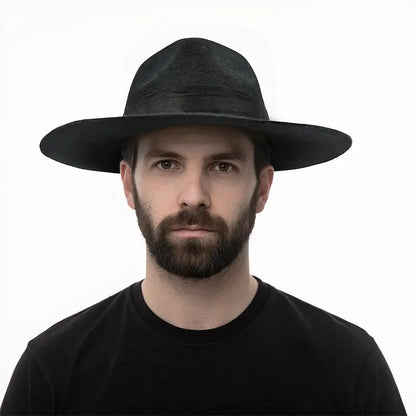 A black felt fedora worn by a man wearing a black shirt.